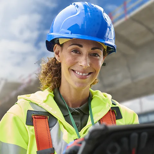 Female surveyor in a hard hat and high vis clothing on a road construction site